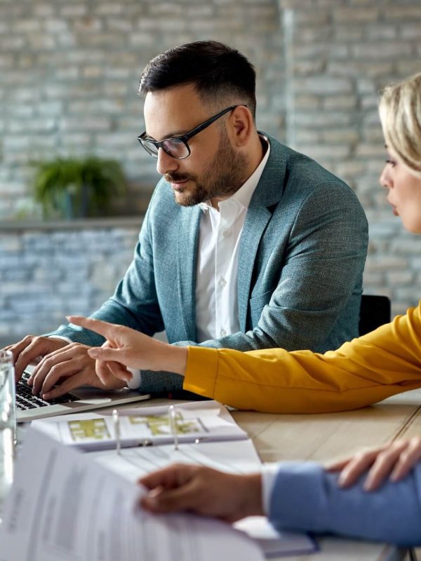 real-estate-agent-using-laptop-while-having-a-meeting-with-a-couple-in-the-office-1-1.jpg